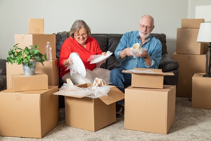 Smiling Senior Couple Packing or Unpacking Moving Boxes